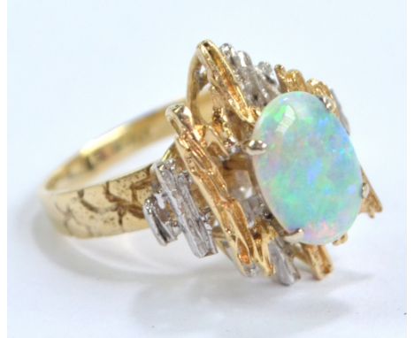 A yellow and white metal opal set dress ring with textured finish to the platform and shoulders, stamped 'K14' to inner band,