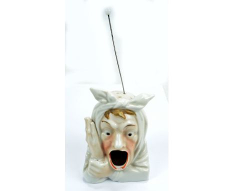 A ceramic hat pin stand modelled as a head of a man with toothache, height 11.5cm (af). CONDITION REPORT: Chip to the lower l