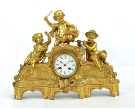 A late 19th century French gilt metal mantel clock surmounted by three putti, the circular dial set with Roman numerals and w
