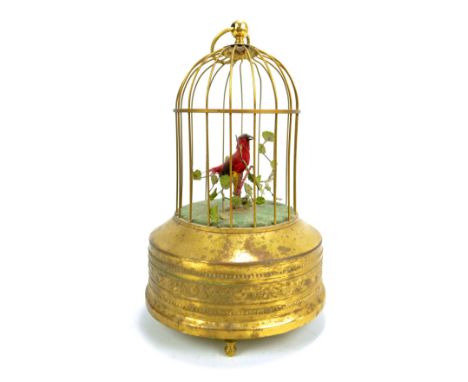 A singing bird automaton on circular base, height total approx 23cm. CONDITION REPORT: Dent to top of cage, some splits to 's