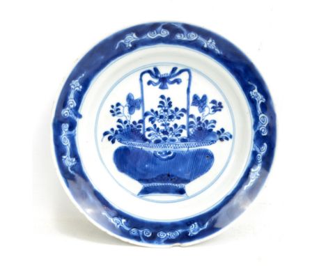 A Chinese porcelain circular plate painted in underglaze blue with basket of flowers within border of clouds on blue ground, 