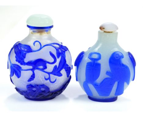 Two Chinese blue carved overlay glass snuff bottles of flat globular forms, one depicting a squirrel amongst blossoming branc