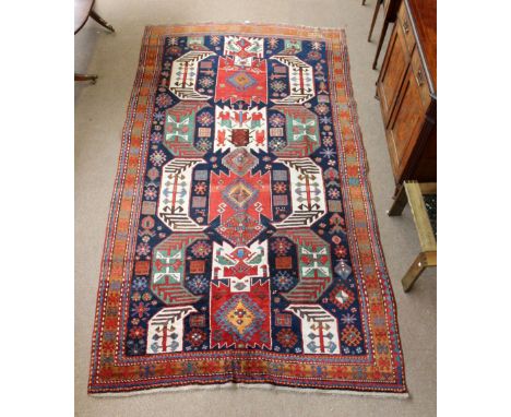 A Lenkoran carpet with geometrical ornamental motifs in green and cream on blue ground within a similarly decorated border, 1