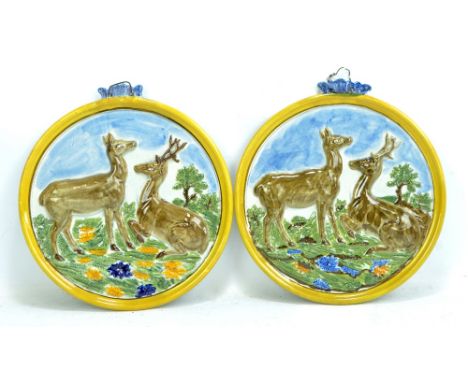 A pair of 19th century pearlware plaques, each relief moulded with a stag and doe in landscape picked out in ochre and blue, 