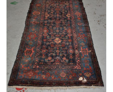 An early 20th Century Persian Islamic woollen floor carpet rug runner. Red ground with repeating geometric panels and borders