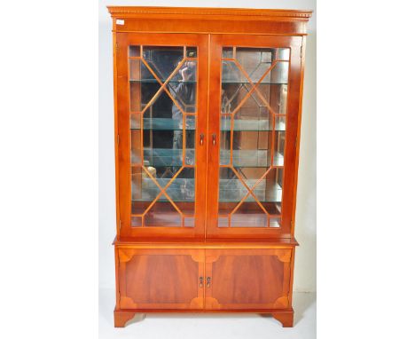 A 20th century George III revival yew wood veneer China display cabinet. The cabinet having a pediment top with dentils along