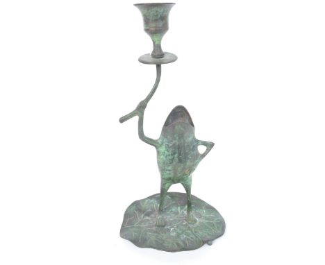A vintage 20th century bronzed metal candlestick in the form of a frog stood upon a lily pad holding candle holder with hand 