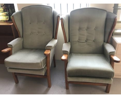 A pair of vintage wooden framed wing back chairs, his &amp; hers, with green velvet upholstery.  