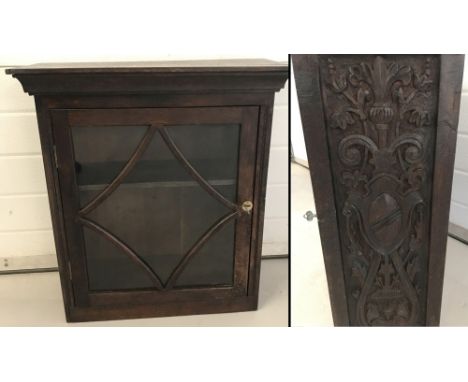 A vintage dark oak wall hanging cabinet with carved detail to sides and glass fronted door. 2 interior shelves, complete with