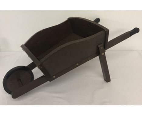 A small vintage handmade wooden wheelbarrow painted brown.  Approx. L75cm x W38cm.