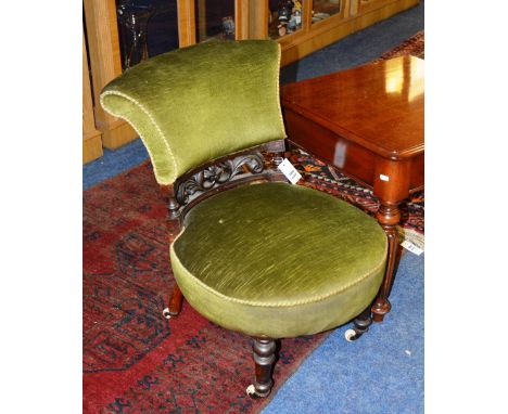 A Victorian mahogany lady's parlour chair, decorated with foliate carving, upholstered in green velour, raised on turned supp