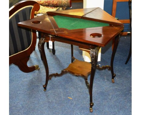 An Edwardian mahogany envelope card table, the swivel top with fold over sections, enclosing felt lined interior, above singl