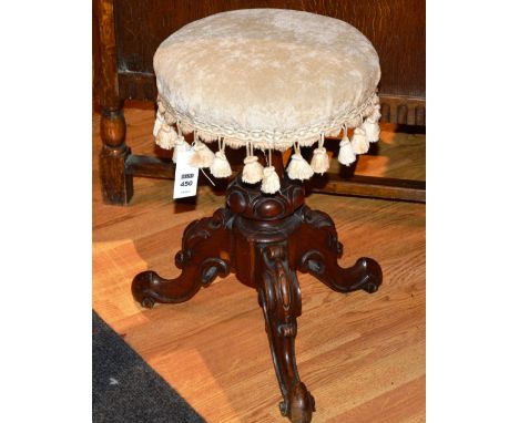 A Victorian mahogany revolving piano stool, with circular upholstered seat, raised on carved tripod supports, 47cm high