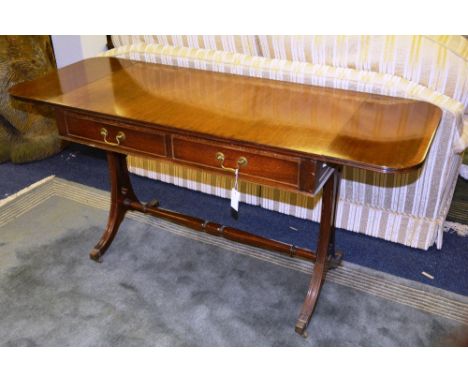 A Regency style mahogany sofa table, with two small drawers and opposing dummy drawers, raised on scroll ends with turned und