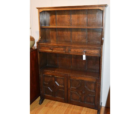 An oak dresser in the Jacobean style, with single shelf above two small drawers, open recess and two carved panelled doors, 1