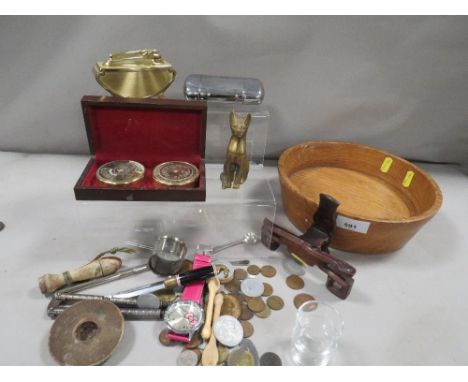 A wooden bowl of collectables, including coins, cigarette lighter etc