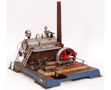 A vintage Wilesco made large live steam plant. Featuring a large flywheel and piston arrangement on a blue metal base. Appear