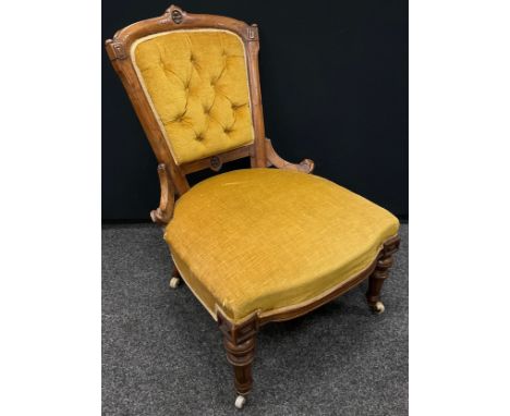 A Victorian walnut salon chair, carved back with deep button upholstery, upholstered and sprung seat, turned legs, ceramic ca