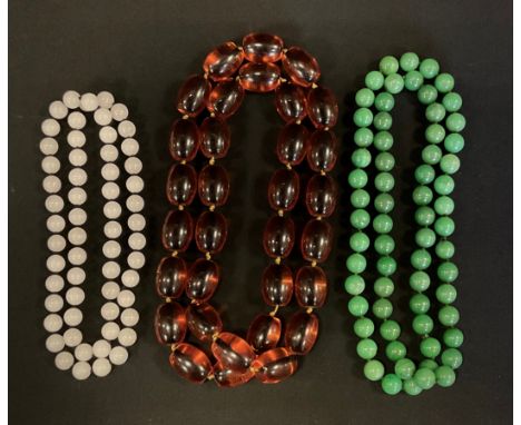 A single strand green bead necklace, possibly jade, 76cm long;  another white stone, 64cm long;    other amber coloured resin