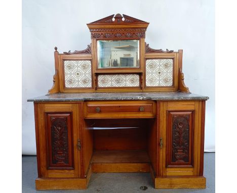 An early 20th century walnut washstand, with a raised tile and mirrored back, on a base with a marble top and two cupboard do