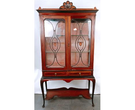 An early 20th century mahogany display cabinet, with two glazed doors above two drawers on cabriole legs, united by a shelf, 