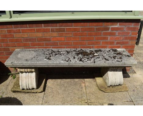 A cast stone garden bench, the slab seat with moulded edges raised on two scroll pedestal supports with associated stone tile