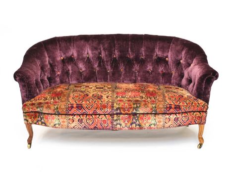 An Edwardian button-back sofa, with roll back and arms, recently upholstered in plum and patterned velour, raised on mahogany