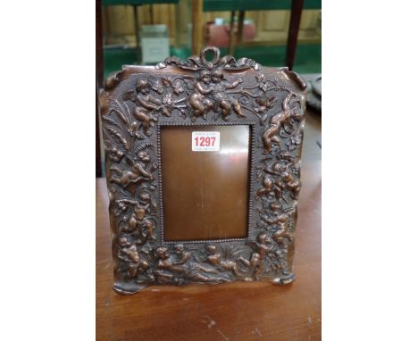 A pair of copper easel back photograph frames, moulded in relief with cherubs, 27cm high.&nbsp; 