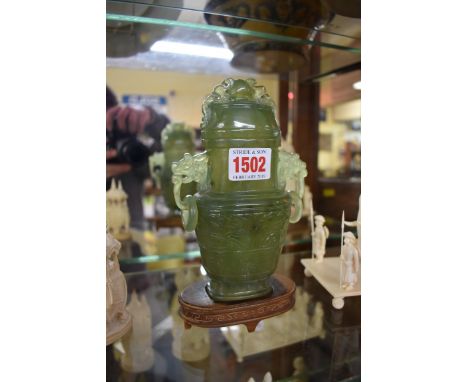 A Chinese carved green jade twin handled vase and cover, 17cm high, on wood stand. 