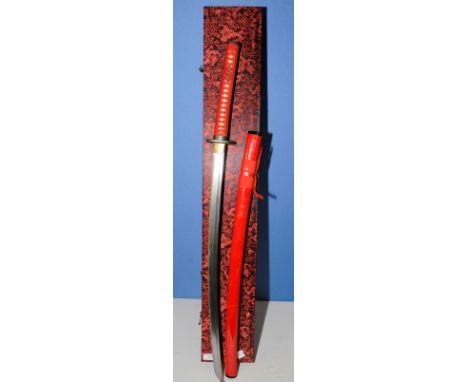 Modern cased Japanese Samurai sword with hard case, canvas sleeve and stand in a red lacquered scabbard with bronze style squ