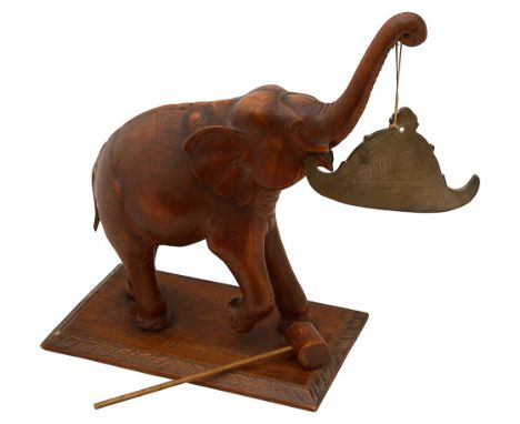 An Indian carved teak elephant gongearly 20th centurythe coiled trunk end holding a shaped metal gong, the base with a leaf c