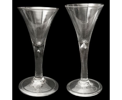 Two mid 18th century plain stem wine glassesboth with drawn trumpet shaped bowls, on plain stems, the taller enclosing an elo