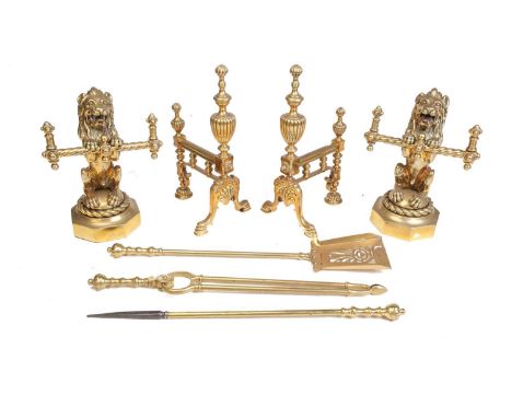 A pair of Victorian cast and gilt brass heraldic sejant erect lion firedogs, each holding a decorative cross bars and mounted