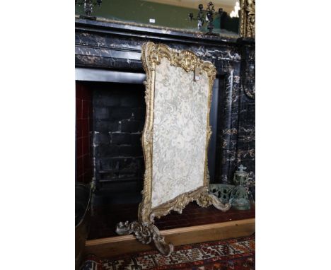 A CARVED GILTWOOD FIRESCREEN, MID-18TH CENTURY, of rococo outline, the cresting centred by a shell on carved trestle scrolll 