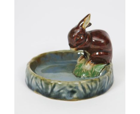 A Doulton Lambeth stoneware rabbit bibelot designed by Harry Simeon &amp;  Vera Huggins,  the circular base modelled with a r