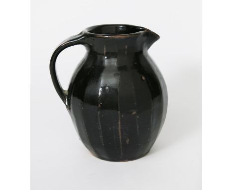 ‡ Trevor Corser (born 1938) a Leach Pottery cut-sided stoneware jug, covered to the foot in a rich tenmoku glaze, impressed s