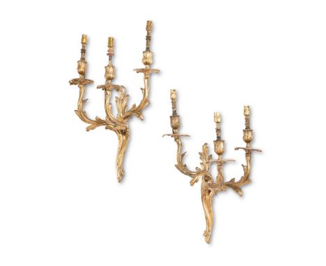 A PAIR OF GILT METAL THREE LIGHT WALL LIGHTS IN LOUIS XV STYLE  EARLY 20TH CENTURY AND LATER FITTED FOR ELECTRICITY  The flor