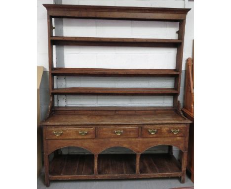 A late 18th/early 19th century oak and pine dresser having open rack top with moulded cornice, two short drawers to base with