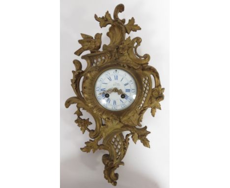 A gilt metal wall clock with an eight day movement and a white enamel dial