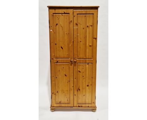 Pair of modern pine wardrobes, each with two panel doors opening to a shelf and hanging space, on bun feet, 177cm high x 82cm