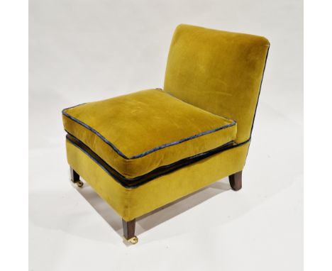 Easy chair upholstered in a mustard-coloured fabric with blue piping, having a loose cushion seat and on wooden square taperi