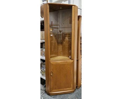 Ercol Windsor ash corner cabinet, model 2138 with smoked glass door opening to adjustable glass shelves, over a panel cupboar