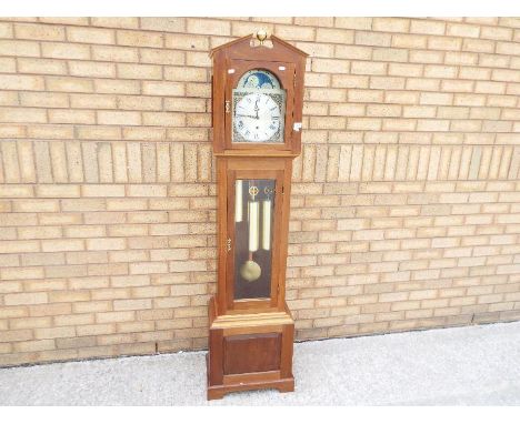 A contemporary longcase clock in light wood case, with architectural top, brass ball finial and glazed opening door, arched b