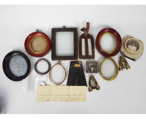 A collection of portrait miniature frames and framed photographs.