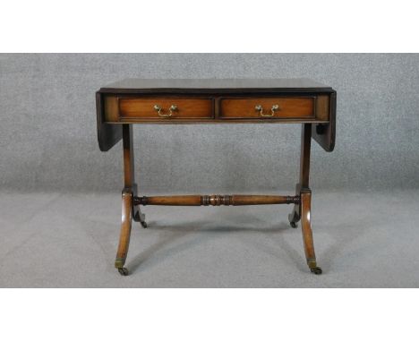 A George III style mahogany sofa table, with two drop leaves, two short drawers, on end supports joined by a turned stretcher