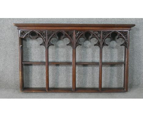 A gothic revival oak wall shelf, with four arched sections, the top of each of trefil form and carved with flowers. H.65 W.11