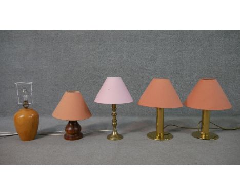 A collection of five table lamps, including a brass pair, with salmon coloured shades, on cylindrical stems with a circular b