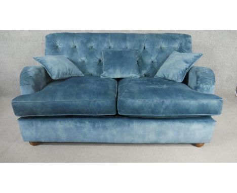 A contemporary Victorian style sofa, upholstered in blue velour, with a buttoned back, on turned bun feet. H.86 W.163 D.96cm.