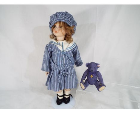 A good quality ceramic dressed doll with glass eyes on a modern stand and a ceramic Steiff original bear with jointed limbs b