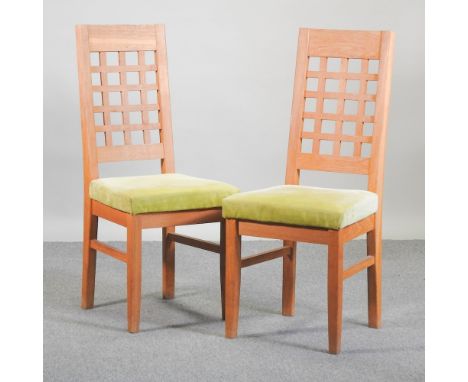 A set of seven modern light oak dining chairs, with green padded seats